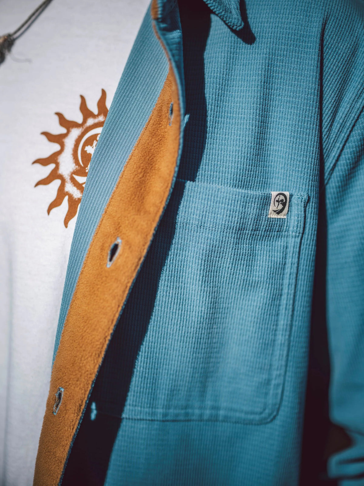 Blue shirt jacket chest pocket with stitched logo patch and brown contrast lining