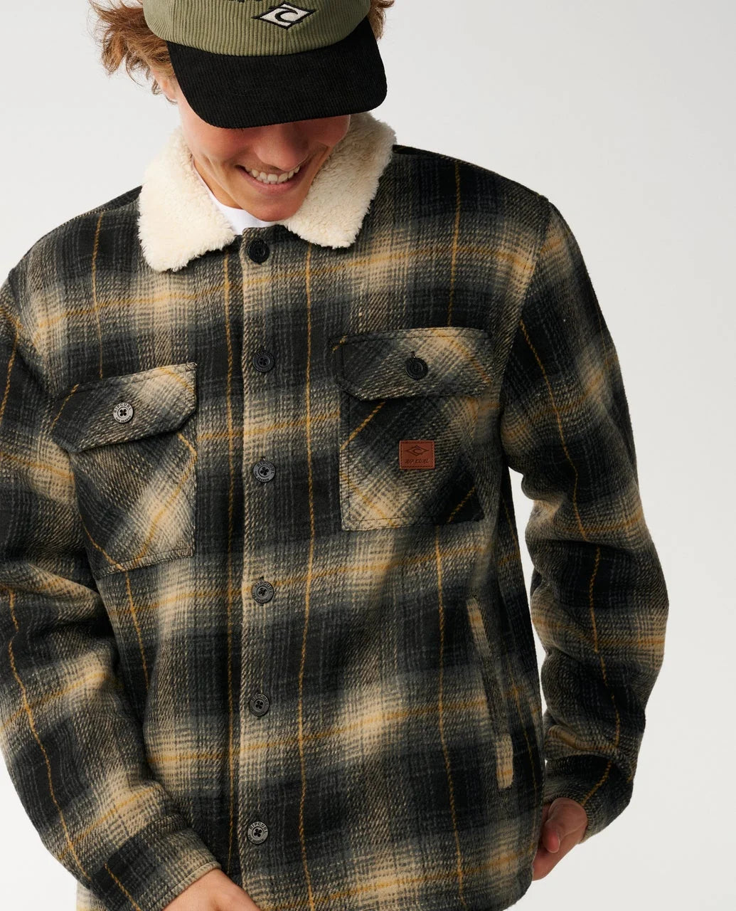 Close-up plaid sherpa-collar snap jacket with chest button pockets and orange label.