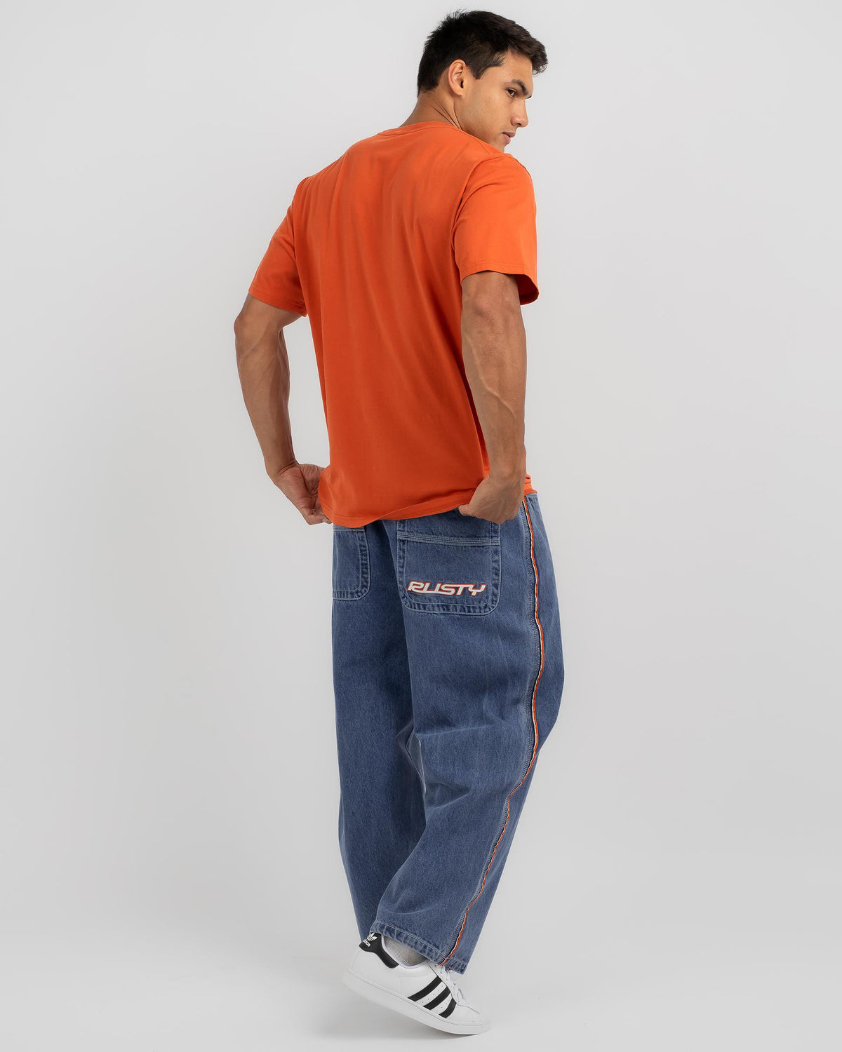 Men's mid-wash blue jeans, back view with stitched logo on pocket and cuffed hem