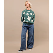 Green crewneck sweater with white floral pattern and ribbed waistband
