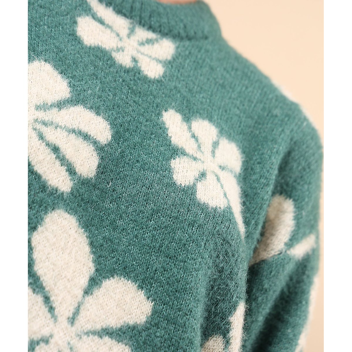 Green knit sweater close-up with large white floral motifs
