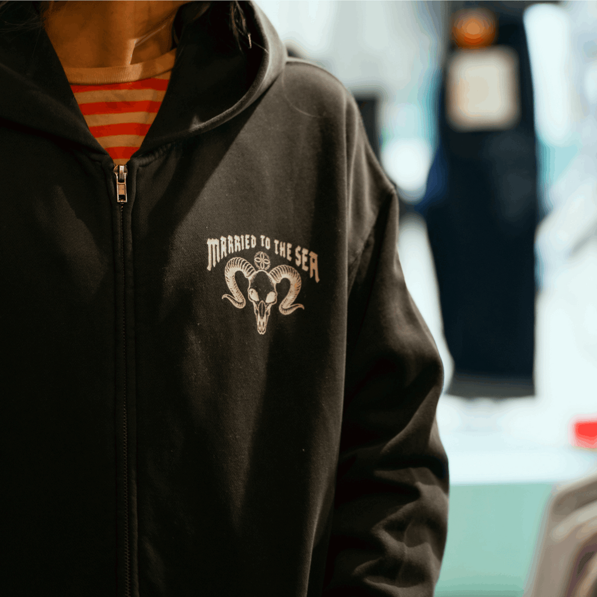 Faded black zip-up hoodie with chest graphic and front zipper
