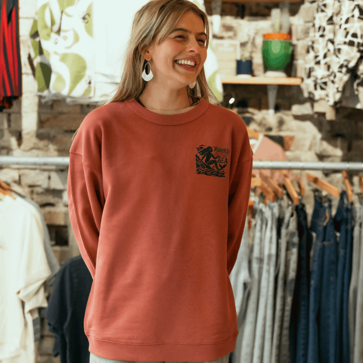 Rust-brown women’s crewneck sweatshirt with chest graphic and ribbed collar