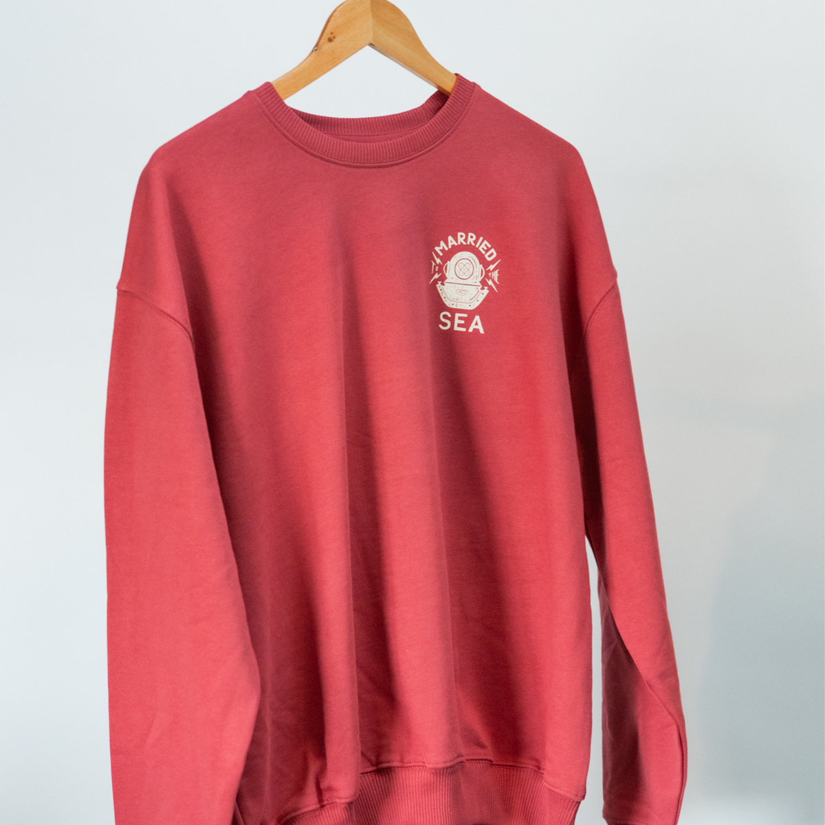 Red crewneck sweatshirt with small 'Married to the Sea' logo graphic on chest.