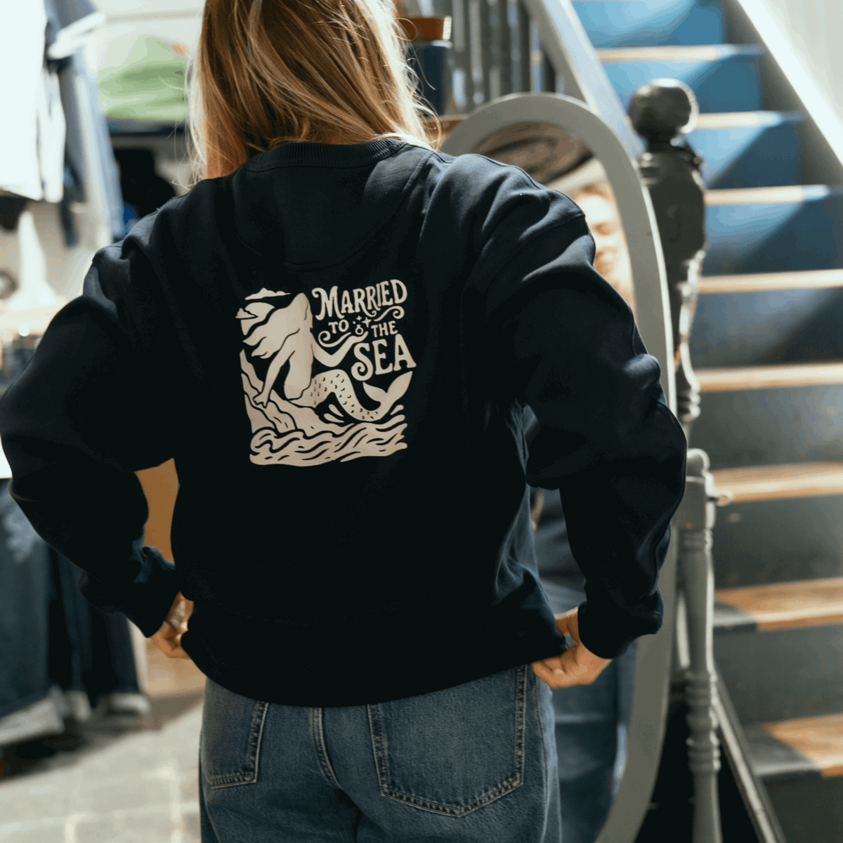 Dark navy crewneck sweatshirt with large 'Married to the Sea' back graphic on model